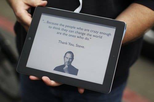An Apple employee holds an iPad with its screen showing a message in memory of Apple founder Steve Jobs, in San Francisco